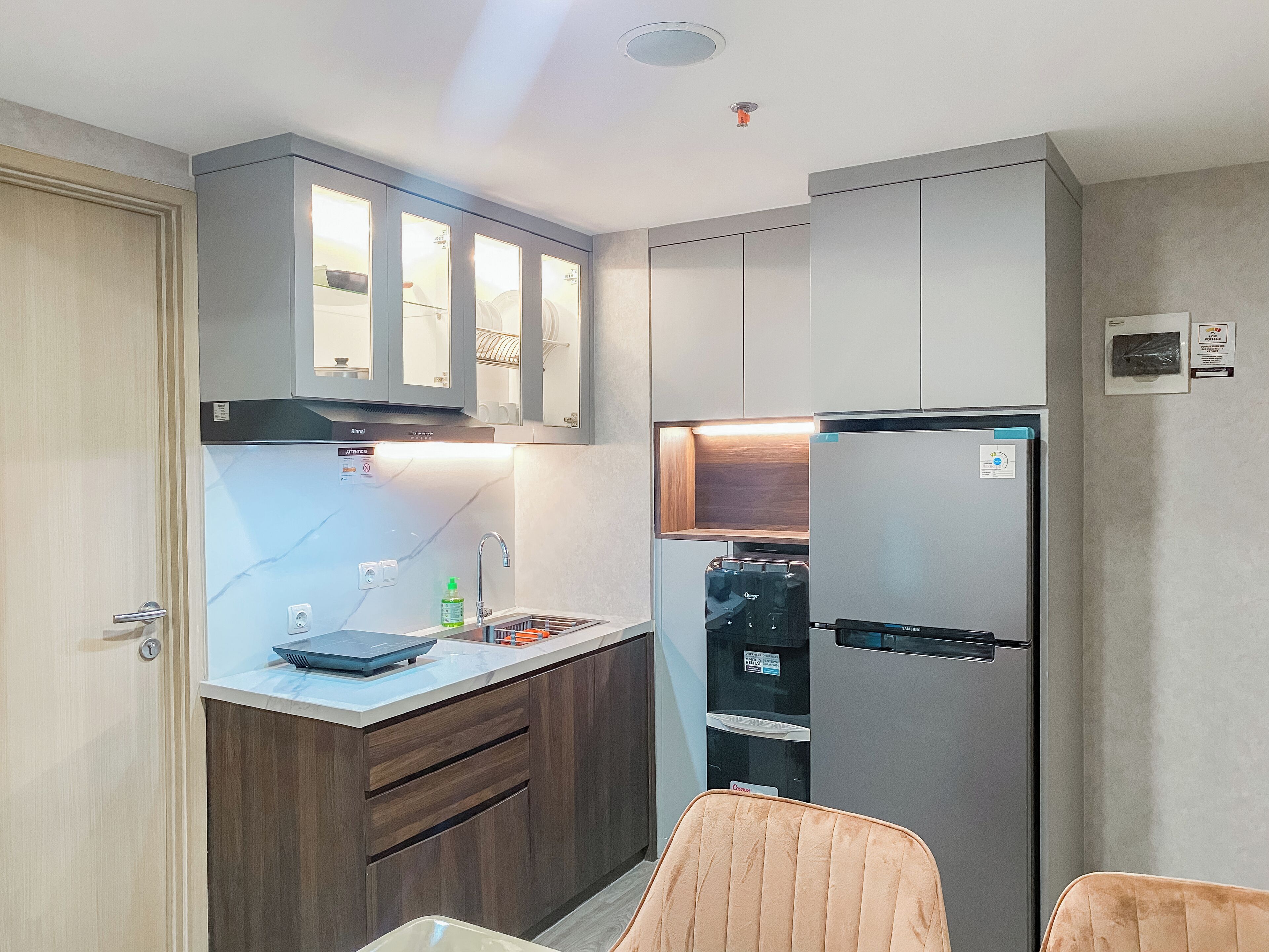 A compact kitchen with a built-in refrigerator, a sink, and wooden cabinets.