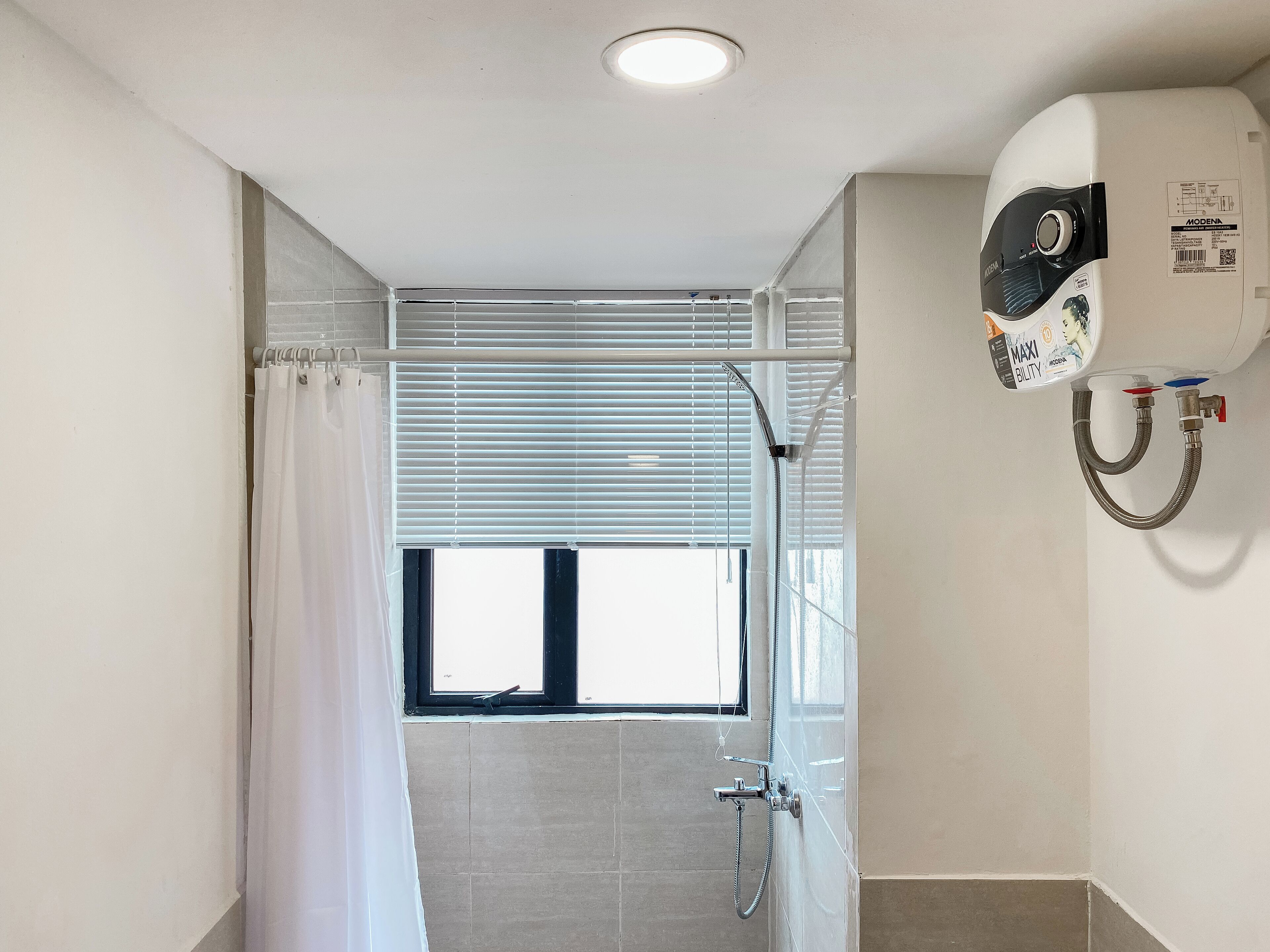 Et badeværelse med brusebad, et vindue med persienner og en loftlampe.