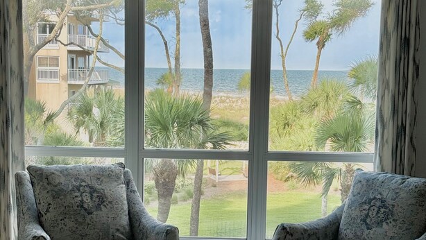 A room with two armchairs facing a large window overlooking a beach and a building. - 4203 Newly Renovated 1BR 2BA Direct Ocean/Beach Views Sofa Bed Soaking Tub (Hilton Head Island)