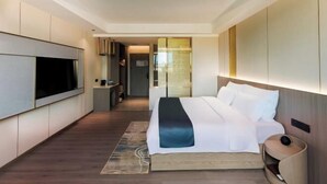 A modern hotel room with a large bed, a flat-screen TV mounted on the wall, and a walk-in closet. - Bolin Hotel (Zhongshan)