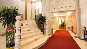 A marble staircase with a red carpet leading to a reception area. - Bolin Hotel (Zhongshan)