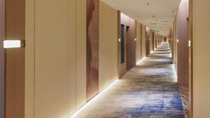 A long, narrow hotel corridor with a patterned carpet and wooden paneling on the walls. - Bolin Hotel (Zhongshan)