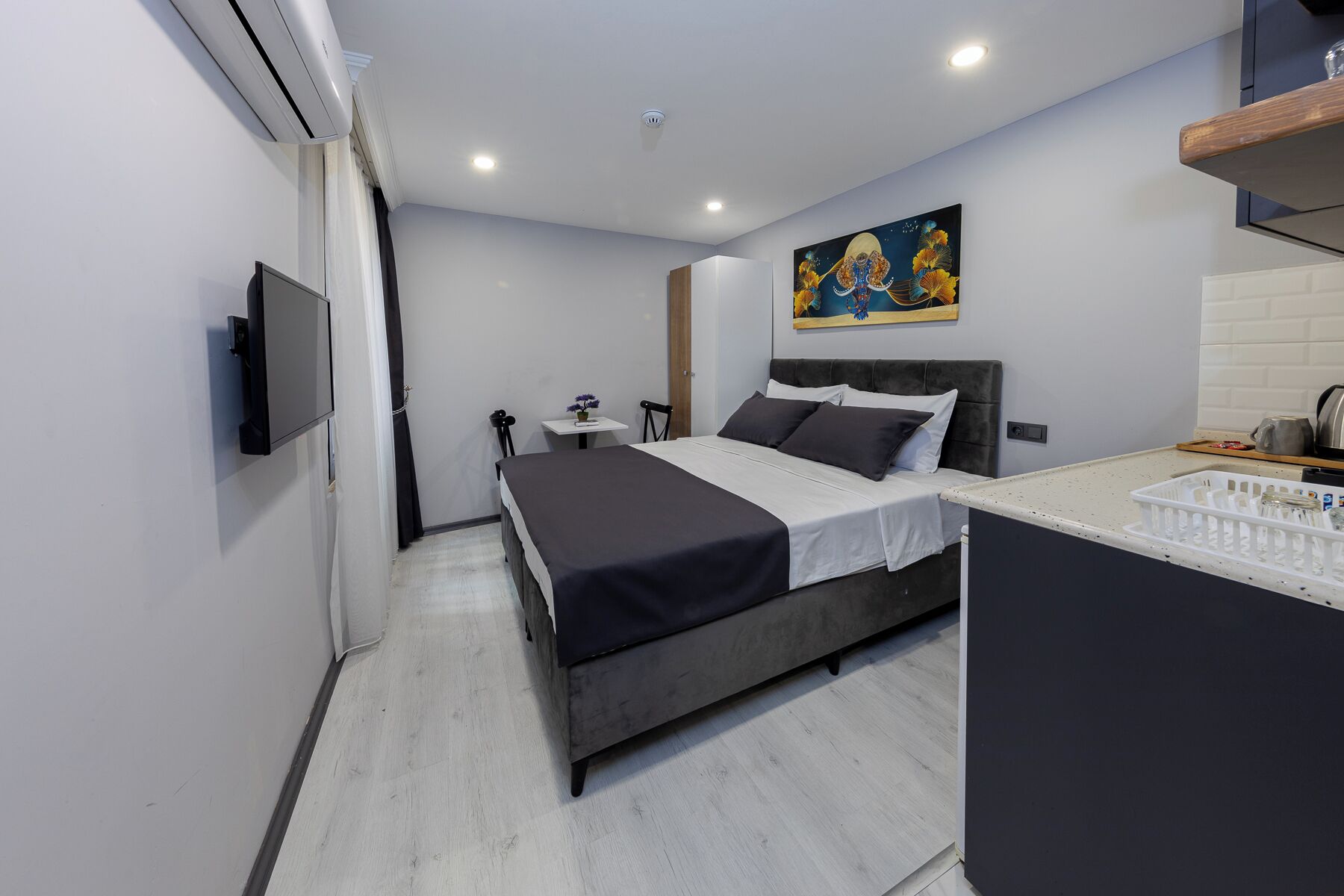 Un dormitorio moderno con cama, mesita de noche y un cuadro en la pared.