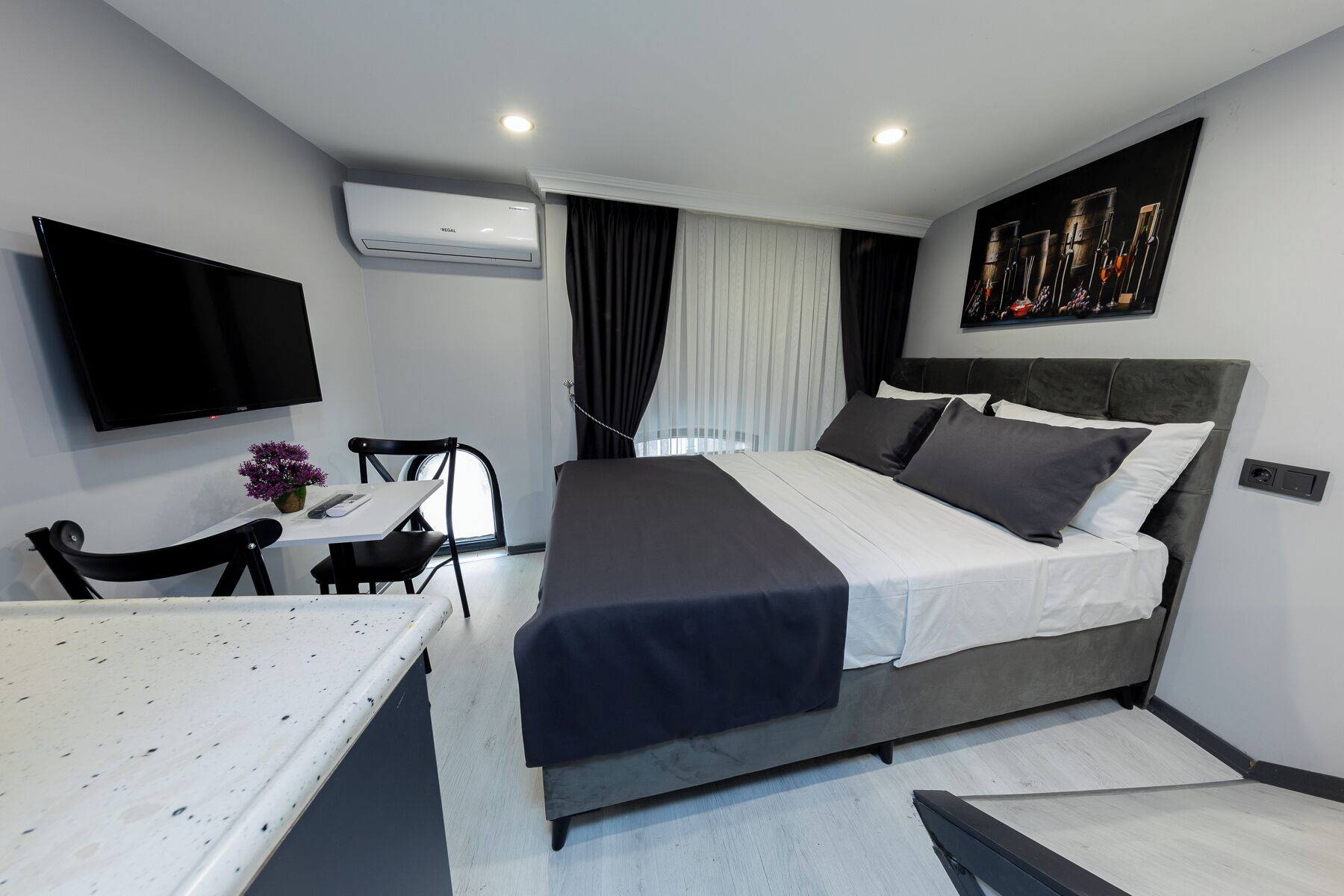 A modern hotel room with a bed, a desk, and a chair.