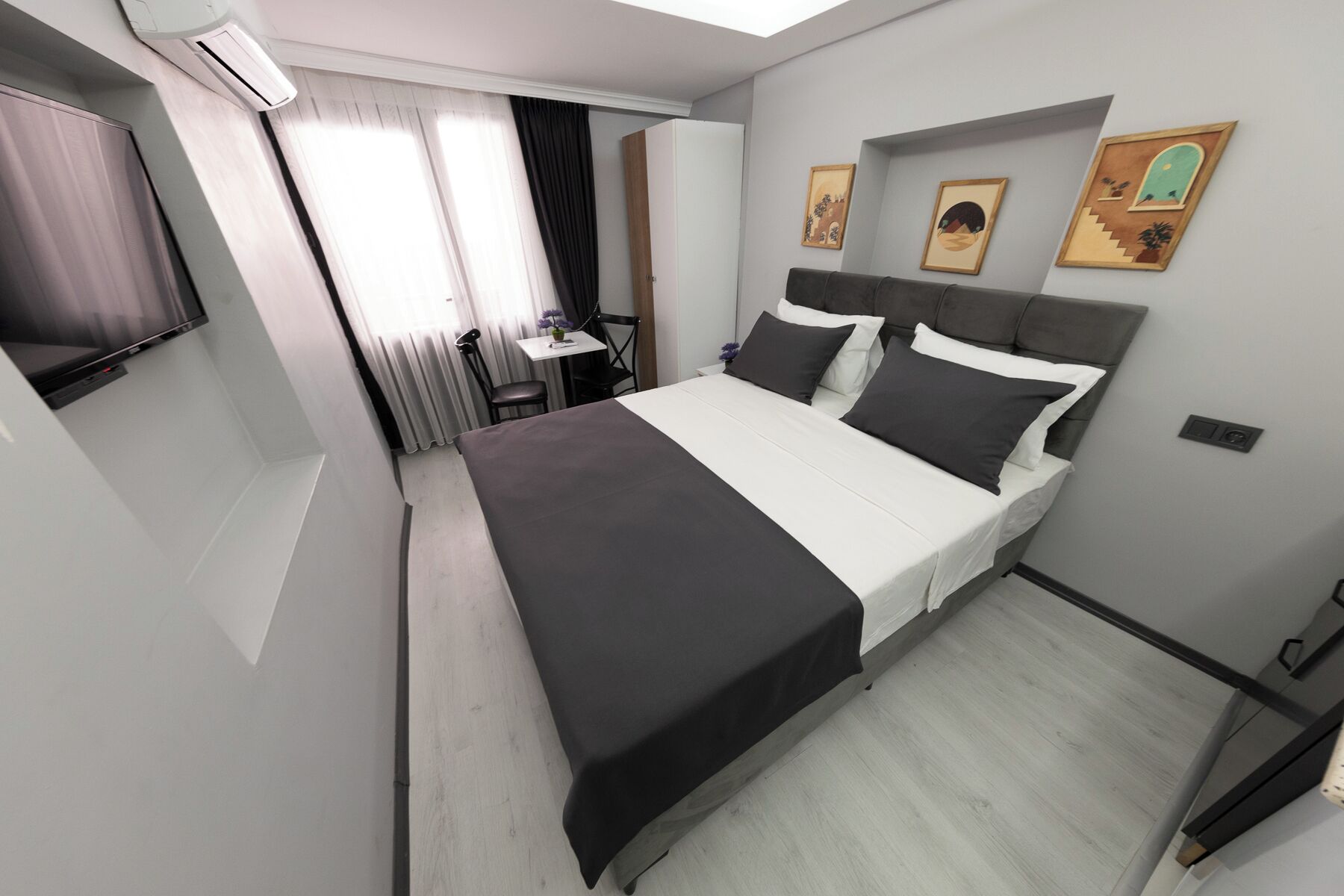 Una habitación de hotel moderna con una cama, un escritorio y un televisor.