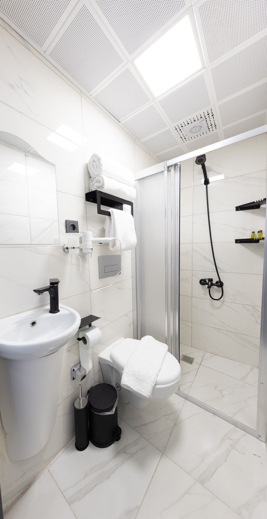 A modern bathroom with a white sink, toilet, and shower.