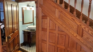 Eine Holztreppe führt zu einem Badezimmer mit Waschbecken und Spiegel.