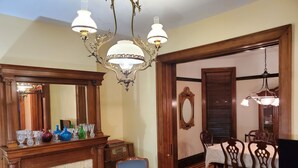 Ein Esszimmer mit Kamin, Holzsesseln, einem Tisch und einer Chandelier.