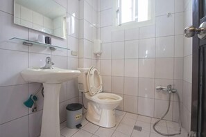 Um banheiro com pia, vaso sanitário e chuveiro.