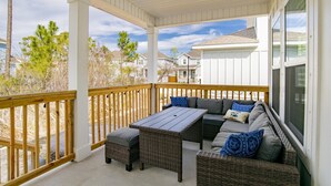 Un espace extérieur abrité, doté d'une terrasse en bois, de meubles en osier et offrant une vue sur les maisons voisines.