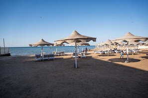 Una platja amb paraigües de palla i gandules.
