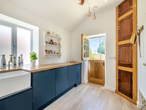 A kitchen with a wooden door, a window, and a shelf with jars.