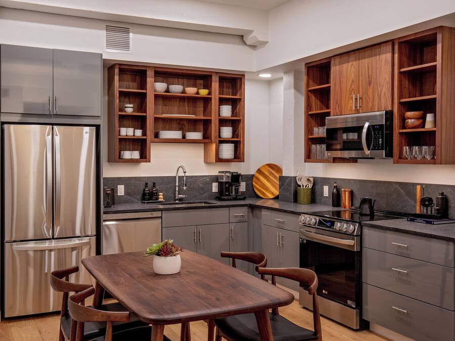 A modern kitchen with stainless steel appliances, wooden cabinets, and a dining area with a wooden table and chairs.