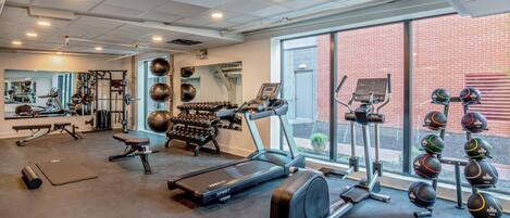 A gym with treadmills, ellipticals, free weights, and exercise balls.