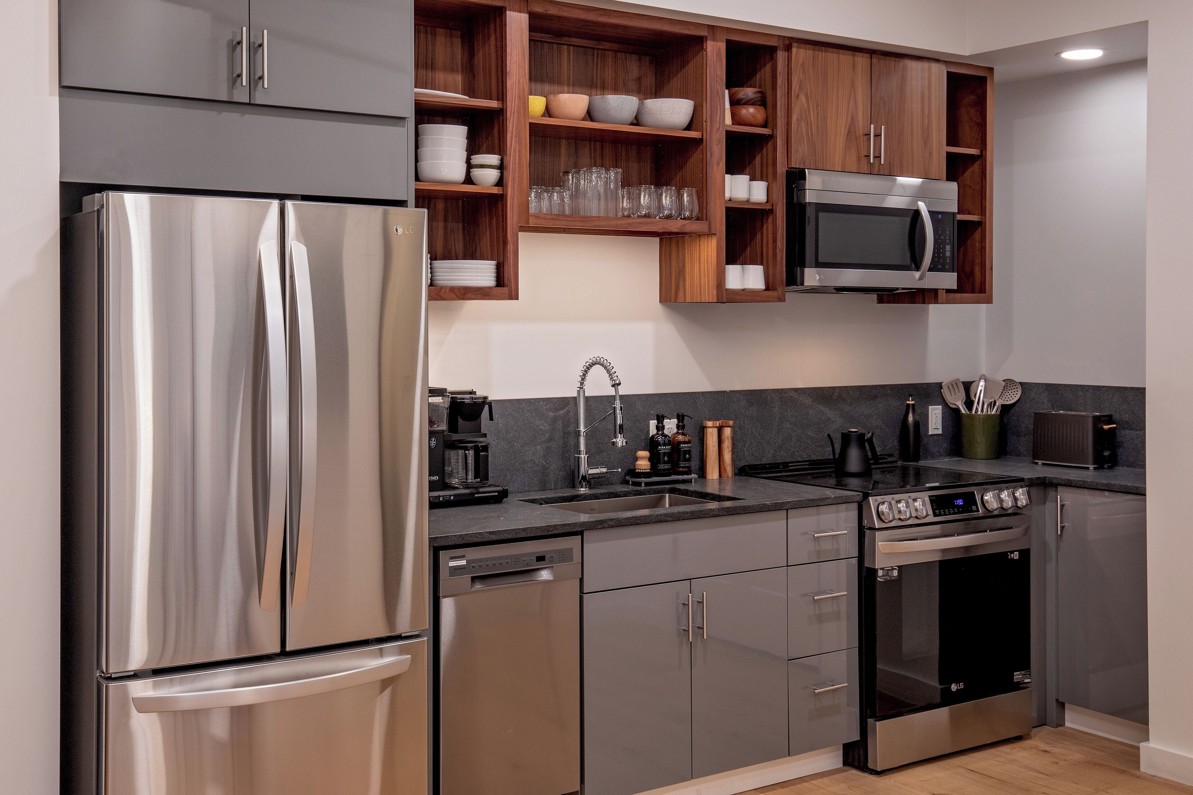 A modern kitchen with stainless steel appliances, wooden cabinets, and a built-in microwave.