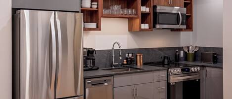Una cocina moderna con electrodomésticos de acero inoxidable, armarios de madera y microondas empotrado.