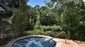 A hot tub surrounded by a stone deck, with a metal ladder for access. - Spacious 2BR+Den Condo at Lodge Brookside (Avon)