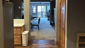 A hallway with a wooden floor leading to a dining area with a table and chairs. - Spacious 2BR+Den Condo at Lodge Brookside (Avon)