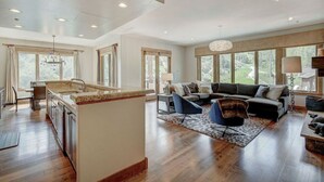A spacious living area with a kitchen island, large windows, and a modern sofa set. - 3BR Condo Luxurious Retreat in Arrowhead (Edwards)