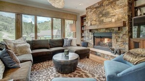 A modern living room with a stone fireplace, large windows, and a cozy seating area. - 3BR Condo Luxurious Retreat in Arrowhead (Edwards)