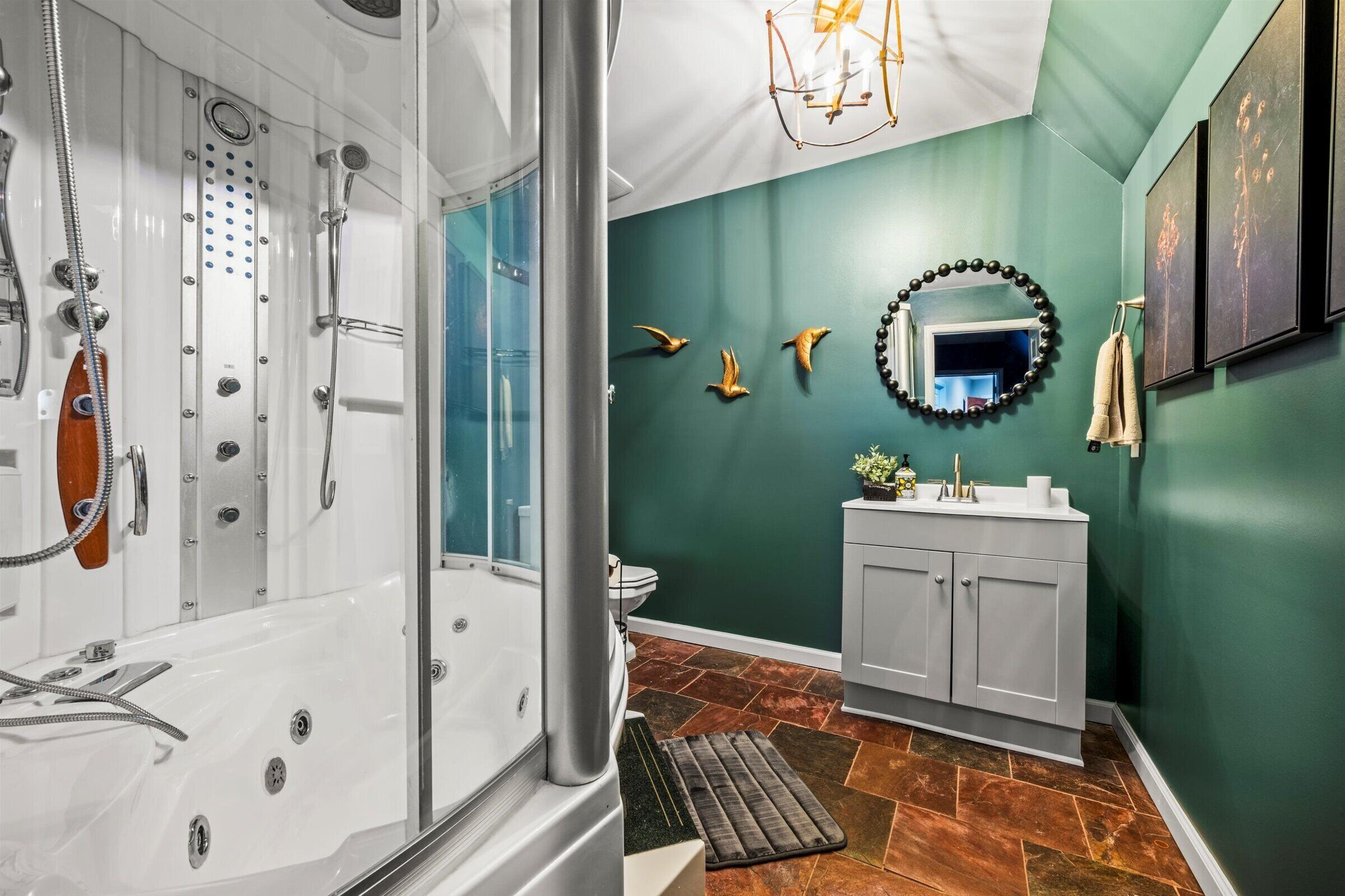 A modern bathroom with a glass-enclosed shower, a white vanity, and a green accent wall.