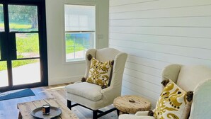 A spacious room with two white armchairs, a wooden coffee table, and a patterned rug.