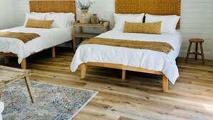 A bedroom with two beds, wooden headboards, a small table, and a hanging light fixture.