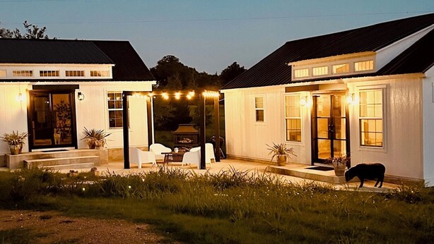 A two-story house with a covered patio area, outdoor seating, and a dog.