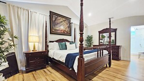 A four-poster bed with a wooden frame, a nightstand with a lamp, a mirror, and a painting on the wall. - Serene Pool Oasis Tampa Vacation Villa (Tampa)