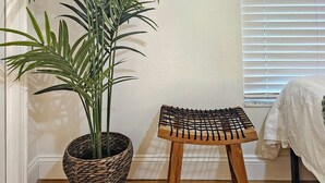 A room with a potted plant, a small wooden stool, and a window with blinds. - Serene Pool Oasis Tampa Vacation Villa (Tampa)