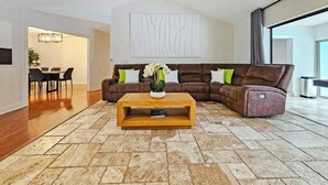 A modern living room with a sectional sofa, a coffee table, and a dining area with chairs. - Serene Pool Oasis Tampa Vacation Villa (Tampa)