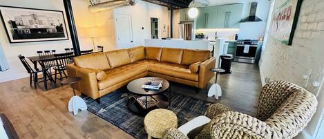Una sala moderna con un sofá modular, una mesa de centro redonda y una silla de fibras naturales.