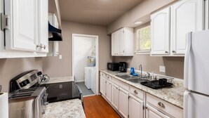 A compact kitchen with white cabinets, a stainless steel toaster, a microwave, and a sink.