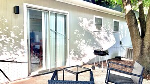 A patio area with outdoor furniture, a grill, and a sliding glass door leading to an interior space.