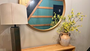 Una consola de madera con una lámpara y un florero con flores amarillas.