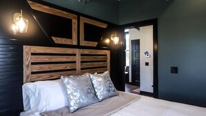 Un dormitorio con cabecera de madera, dos almohadas y lámparas de noche.
