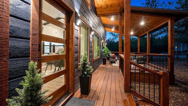 A wooden deck with a covered area, large windows, and potted plants. - Sauna, Bar, Big Patio, Hot Tub, Fire Pit & Pets (Broken Bow)