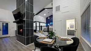 A modern dining area with a glass table, black chairs, and a fireplace. - Sauna, Bar, Big Patio, Hot Tub, Fire Pit & Pets (Broken Bow)