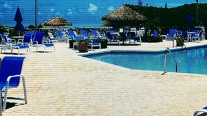 Zona junto a la piscina con sillones reclinables azules y una piscina pequeña.