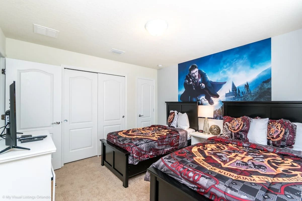Ein Schlafzimmer mit zwei Betten, einem Schreibtisch und einem großen Poster an der Wand.