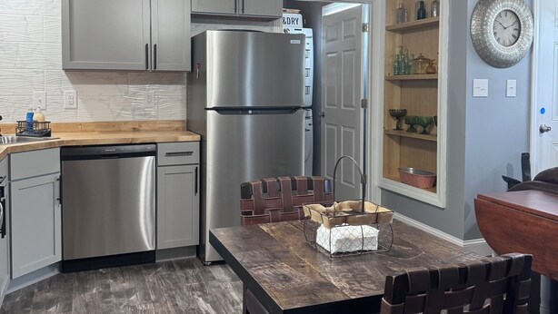 A modern kitchen with stainless steel appliances, wooden ceiling, and a dining area with a wooden table and chairs. - Charming single family Cottage, pet friendly, close to Prov, Woon, MA & highways (Lincoln)