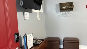 A room with a wooden ceiling, a mounted TV, a desk with a computer, a 'Welcome' sign, a 'WiFi' sign, and a wine rack. - Charming single family Cottage, pet friendly, close to Prov, Woon, MA & highways (Lincoln)