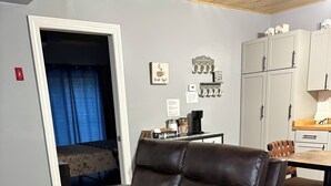 A brown leather sofa in a room with a wooden floor, a dining table, and cabinets. - Charming single family Cottage, pet friendly, close to Prov, Woon, MA & highways (Lincoln)