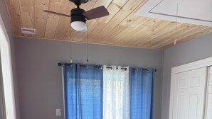 A bedroom with a bed, a ceiling fan, a window with curtains, and a door. - Charming single family Cottage, pet friendly, close to Prov, Woon, MA & highways (Lincoln)
