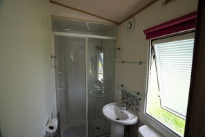 Een douche, handdoeken, zeep, toiletpapier