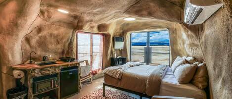Una habitación acogedora con cama, un escritorio pequeño y ventana con vista a la playa.