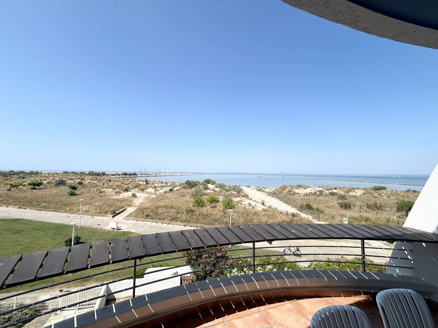 A balcony with a view of a beach and dunes.