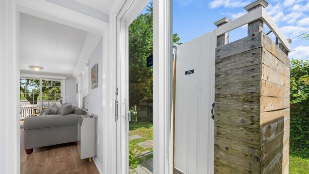 A modern interior with a grey sofa and a white door leading outside. - Relax at Hilltop Hideaway, Near the Shore (Dennis Port)