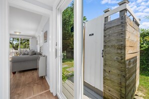 Un interno moderno con un divano grigio e una porta bianca che dà all'esterno.