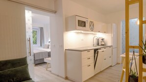A modern kitchen with white cabinets, a coffee machine, and a window with curtains.